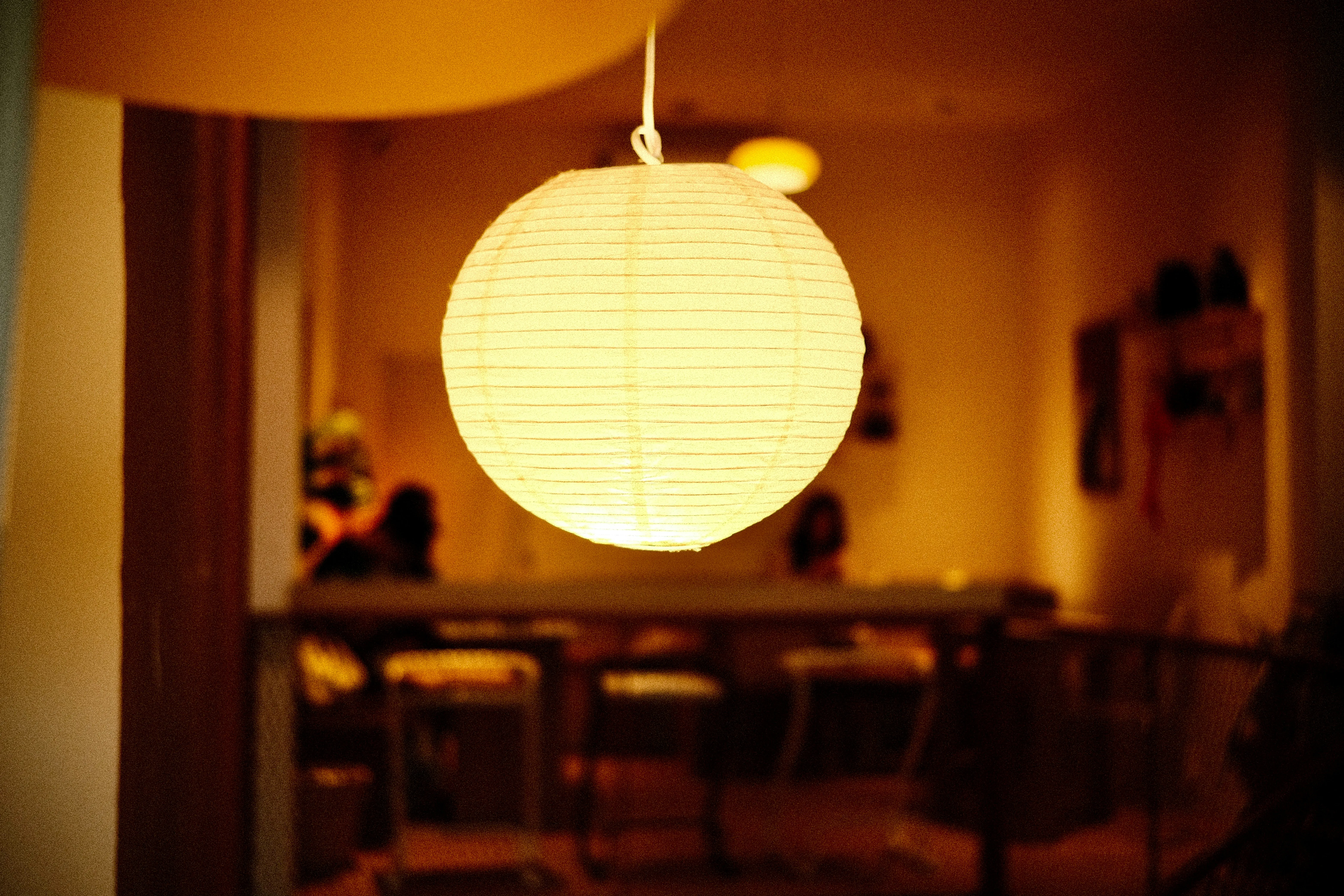 A warm paper lamp hangs in warm orange room.